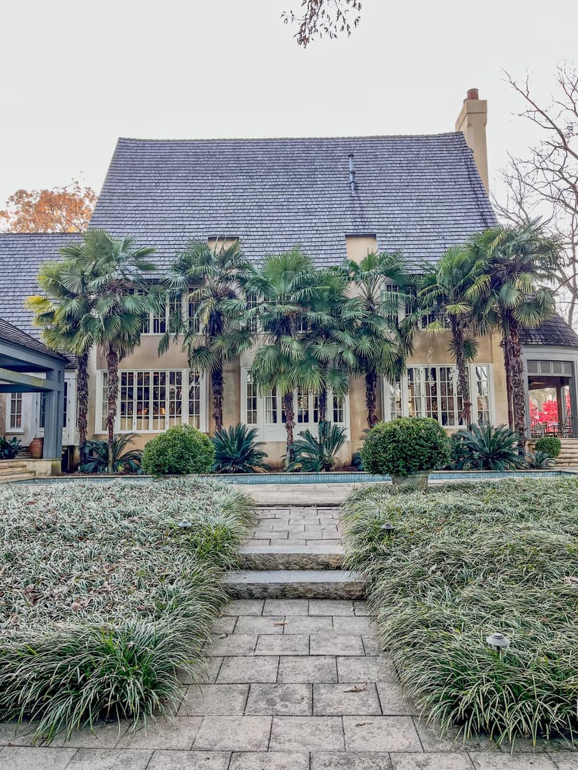 Charming house with palm trees and lush landscaping in front. Elegant architecture and greenery.